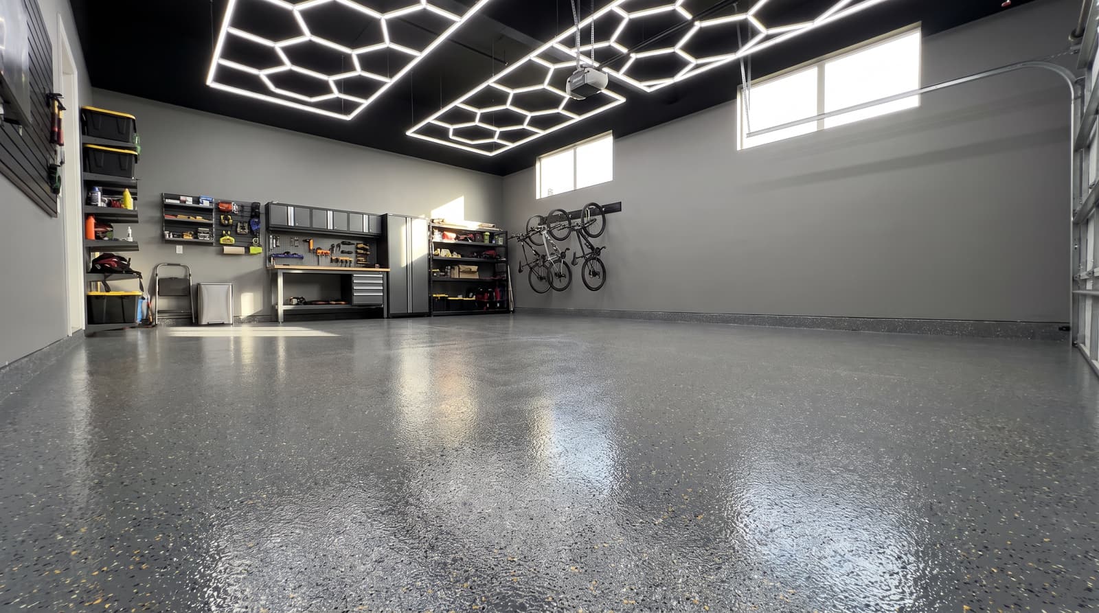 Gray flake epoxy garage floor reflecting hexagonal LED shop lights